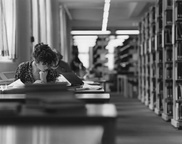 Black and white photo of woman studying in library