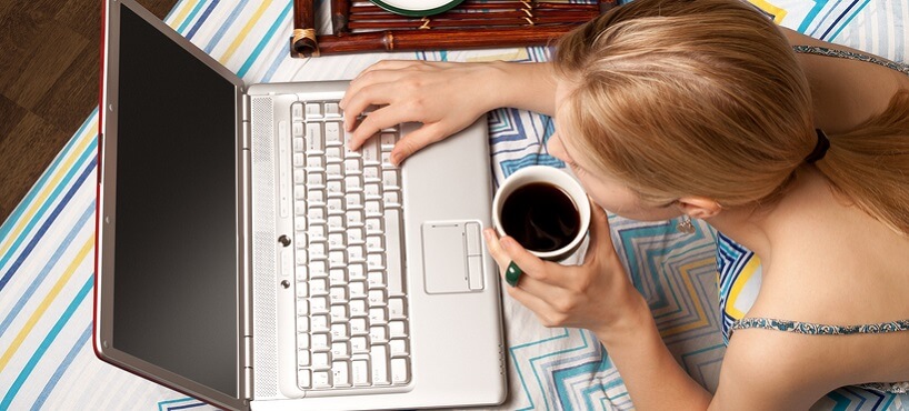 Student at home working on a computer and drinking coffee